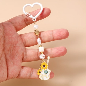 Détail du porte-clés musical perlé avec guitare et tournesol sur fond rose