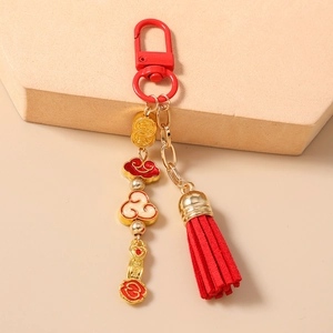 Close-up of Chinese style red tassel keychain with gold auspicious cloud and ingot charms