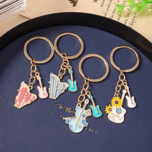 Detailed close-up of musical instrument keychains with harp, guitar and cello in a blue tray