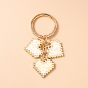 Detail of pixel heart keychain with white enamel pattern and golden metal links