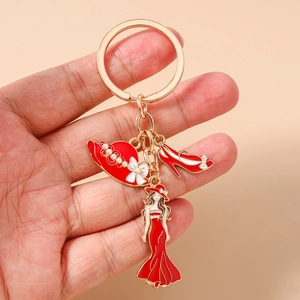 Détail d'un porte-clés doré avec breloques en émail rouge en forme de chapeau et talon