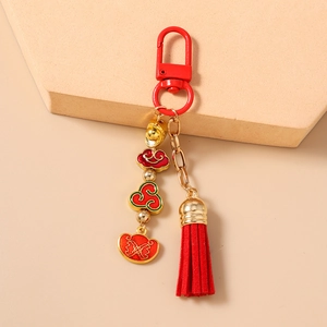Detail of Chinese style keychain featuring red tassels and gold enamel ingot charms