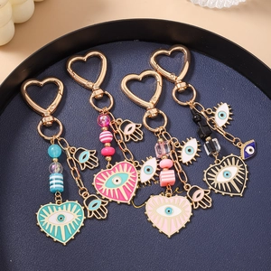 Detail of colorful Evil Eye heart keychains with gold charms and beaded chain on a tray