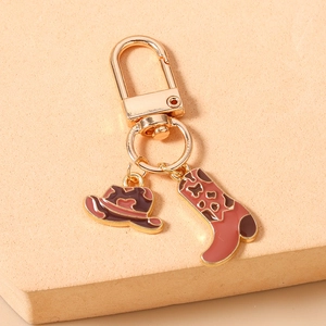 Détail d'un porte-clés doré avec charms chapeau de cowboy et bottes au motif tacheté