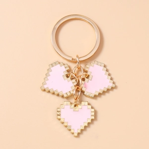 Close-up of pink pixel heart charms with gold serrated edges on a gold keychain