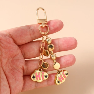 Detail of gold beaded keychain featuring pink cloud charms with HI lettering design