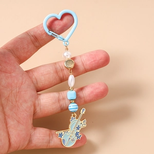 Détail d'un porte-clés violon bleu avec perles et motifs de tournesol tenu dans la main