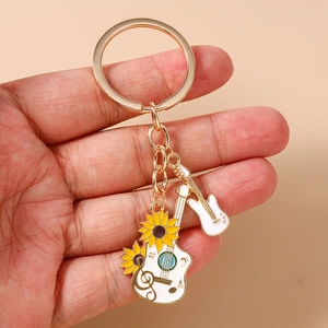 Detail view of guitar charms with sunflower and music notes on golden keychain