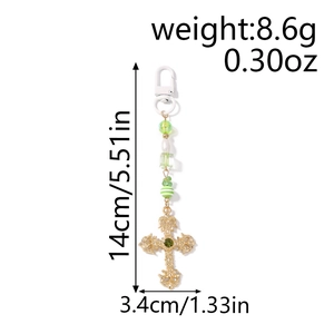Detail of beaded keychain showing green striped beads and a gold cross with green gem