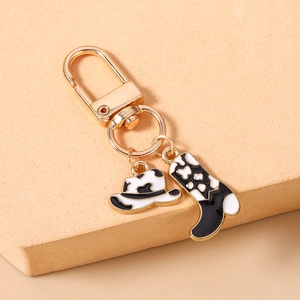 Détail du porte-clés chapeau et botte de cow-boy avec motif vache et fermoir doré