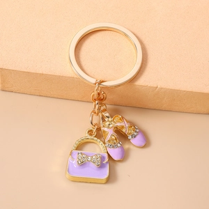 Detailed close-up of purple enamel handbag and ballet shoes key chain with crystals