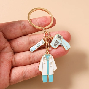 Détail du porte-clés médical doré avec pendentifs en émail de thermomètre et blouse blanche