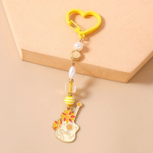 Détail du porte-clés guitare avec motif tournesol, perles blanches et fermoir en forme de cœur