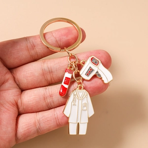 Détail du porte-clés médical avec pendentifs émaillés en forme de thermomètre et blouse