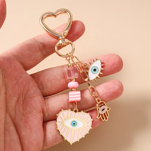Detail of a golden heart keychain with pink Evil Eye and Hamsa Hand lucky charms