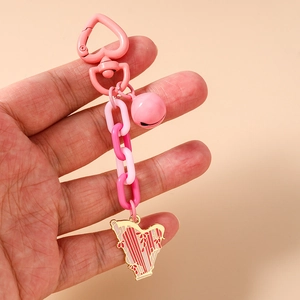Dettaglio del ciondolo arpa in smalto rosa con chiusura a cuore e campanellino