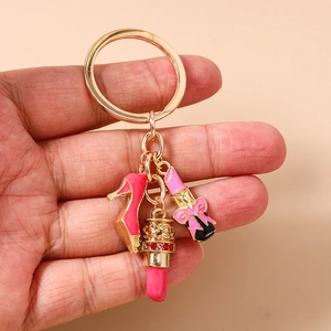 Detail of keychain featuring pink high heels, lipstick and perfume bottle charms on gold ring