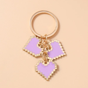 Detailed view of purple pixel heart keychain charms with gold metal rings and finish