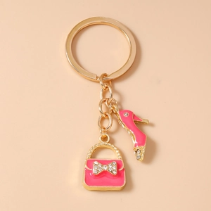 Close-up of golden keychain with pink enamel high heel shoe and handbag charms