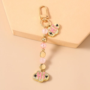 Detail of pink enamel cloud charm with HI lettering on a gold beaded keychain