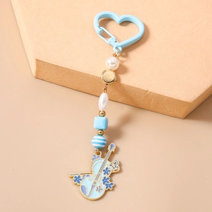 Détail du porte-clés violon bleu clair avec fermoir coeur, perles et pendentif émaillé