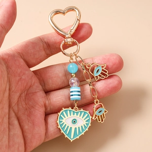Close-up of golden heart evil eye keychain with hamsa hand charms and blue beads