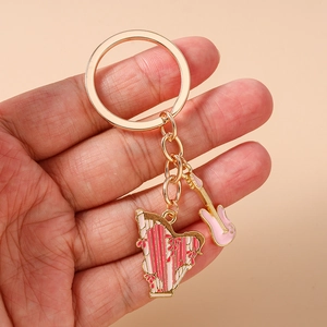 Detail view of gold-tone music keychain with pink enamel electric guitar and harp charms