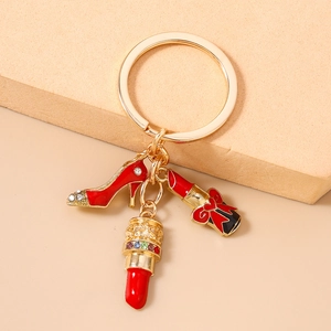 Detail of gold keychain with sparkling red high heel and lipstick charms with rhinestones