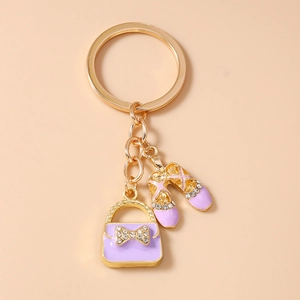 Detail of purple enamel handbag and ballet shoes charms with crystal bow on gold keychain