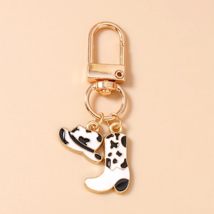 Détail des breloques chapeau et botte de cow-boy à motif vache sur porte-clés doré