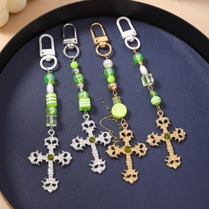 Gothic cross keychains with green crystals and striped beads detail on a navy tray