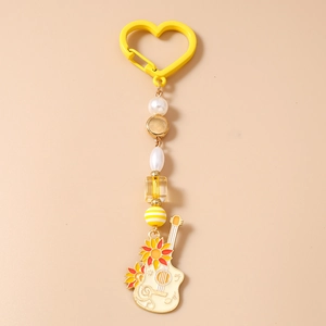 Détail d'un pendentif guitare blanc avec motif tournesol et chaîne de perles jaunes
