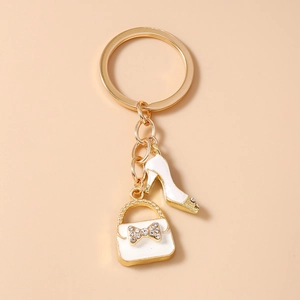 Detailed macro of golden keychain with white enamel high heel and handbag charms