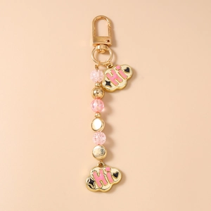 Close-up of golden beaded keychain with pink clouds and Hi engraving detail