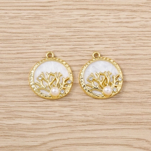 Détail de deux pendentifs corail dorés avec perle blanche et zircons étincelants