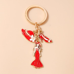 Détail des breloques rouges d'escarpin et de chapeau sur un porte-clés doré émaillé