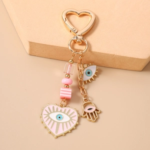 Detailed pink Evil Eye and Hamsa hand charms on a golden alloy heart keychain