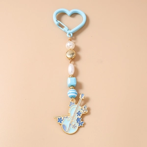 Détail du porte-clés violon avec crochet cœur bleu, perles et pendentif floral en émail