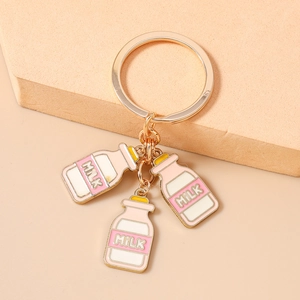 Detailopname van een gouden sleutelhanger met drie kleurrijke emaille melkfleshangers