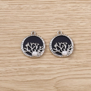 Vue détaillée de pendentifs arbre de vie argentés avec incrustation noire et perle blanche