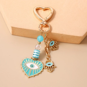 Detail of Hamsa Hand and Evil Eye keychain with blue beads on a heart carabiner