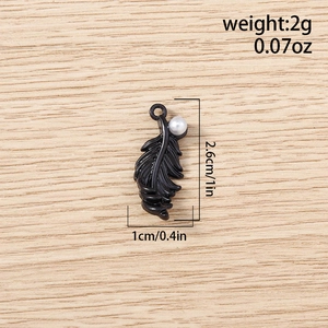 Detailed macro view of a black enamel feather pendant with pearl inlay for DIY jewelry crafts
