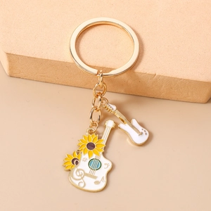Detail of a white electric guitar keychain with sunflower charm and golden metal hardware