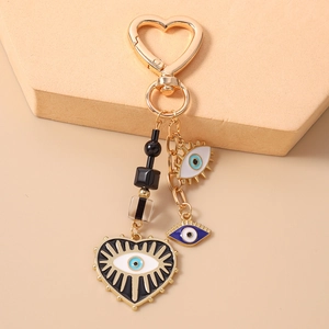 Macro detail of golden heart-shaped evil eye keychain with enamel charms on stone decor