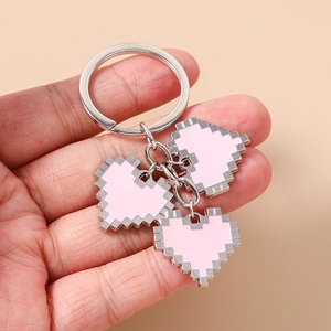 Detail of three pink pixel heart pendants on a silver alloy keychain held by hand