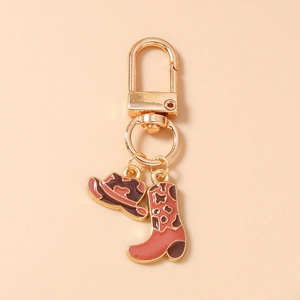 Détail d'un porte-clés de cow-boy avec pendentifs chapeau et botte en émail rose et brun