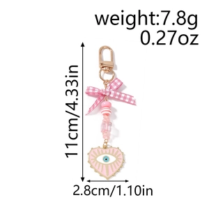 Detail view of pink bow keychain with evil eye heart pendant measuring 11cm in height