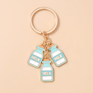Detailopname van een gouden sleutelhanger met blauw-witte emaille melkfles hangers