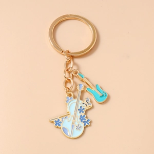 Close-up of enamel violin and guitar keychain charms on a golden metal keyring