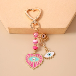 Close-up of pink beaded evil eye keychain with heart clasp and hamsa hand charm